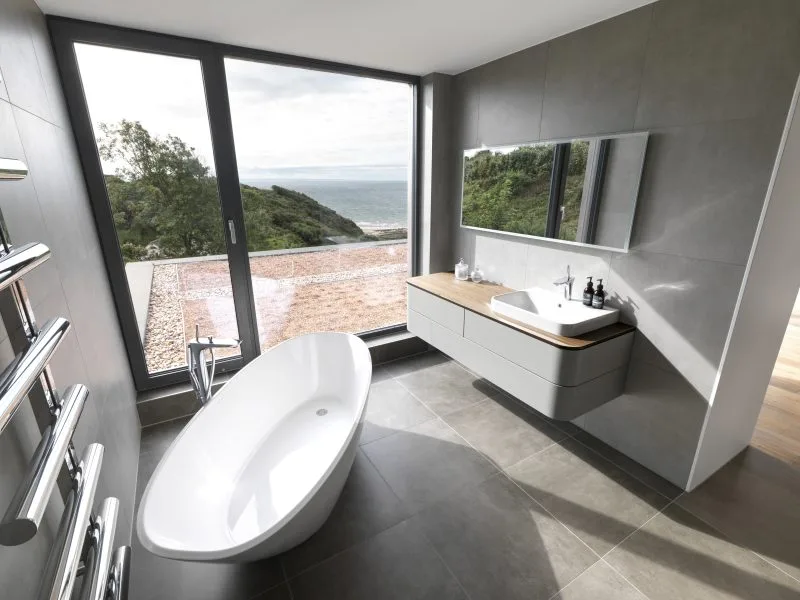 A modern bathroom with a free-standing bath tub and floating sink unit that looks out onto a great view.